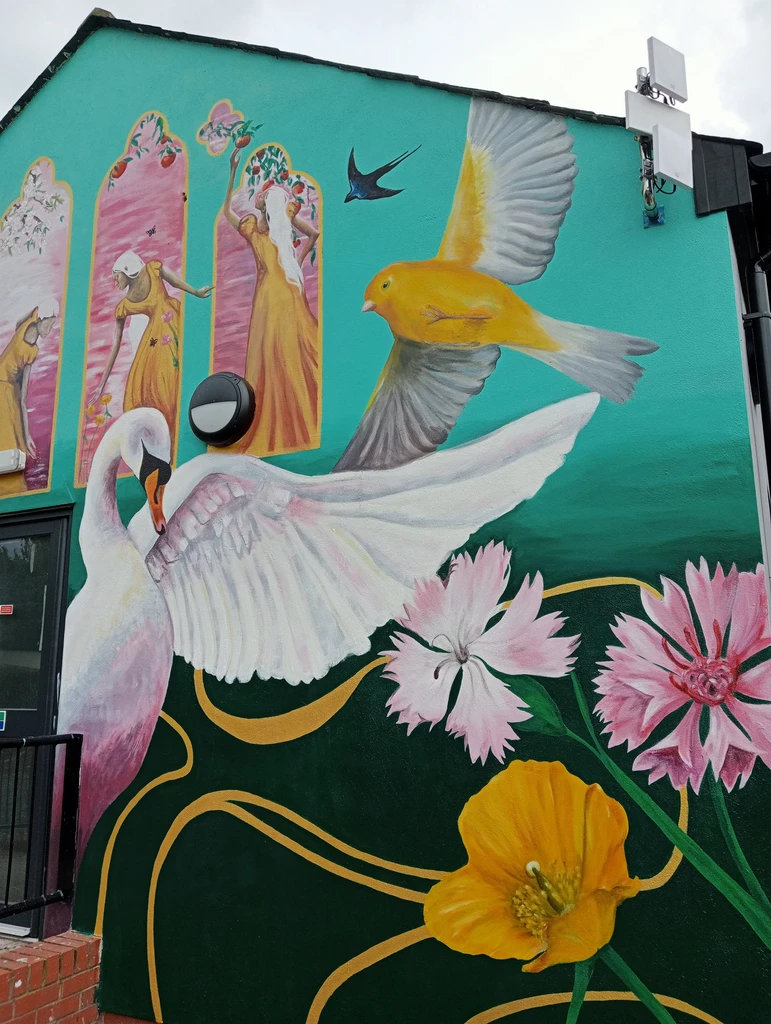 A recently painted wall-mural with a large swan, yellow canaries, and four decorative panels depicting the changing seasons