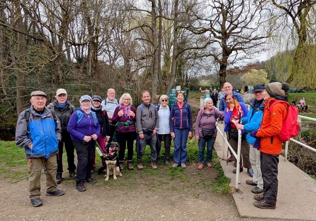 Over a dozen members of the group pose for a photo by a short bridge