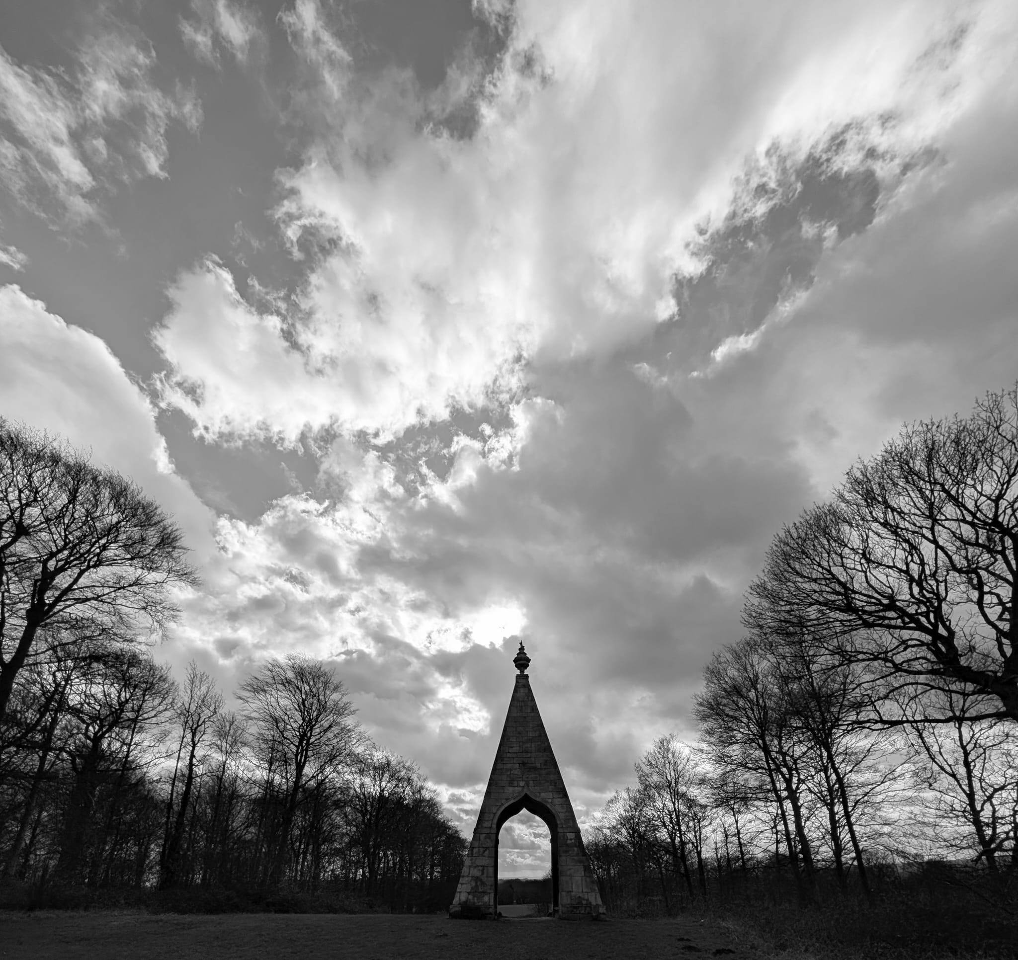 A black and white photo of the Needle's Eye monument at a distance